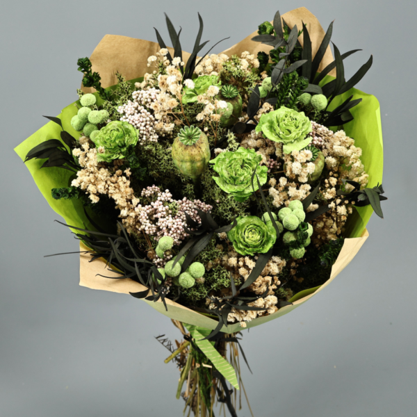 Ramo redondo de flores preservadas con rosas verdes, craspedia beige, eucalipto oscuro y envoltorio kraft, sobre fondo gris neutro. Estilo decorativo natural y silvestre.